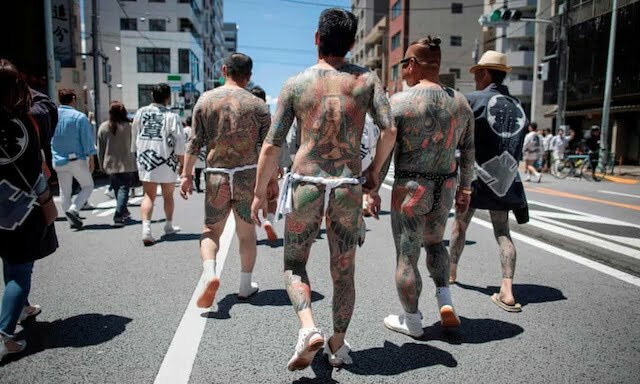 Một nhóm người với hình xăm truyền thống Nhật Bản, liên quan đến Yakuza, đi bộ qua quận Asakusa trong lễ hội Sanja Matsuri hàng năm ở Tokyo. Ảnh: AFP.